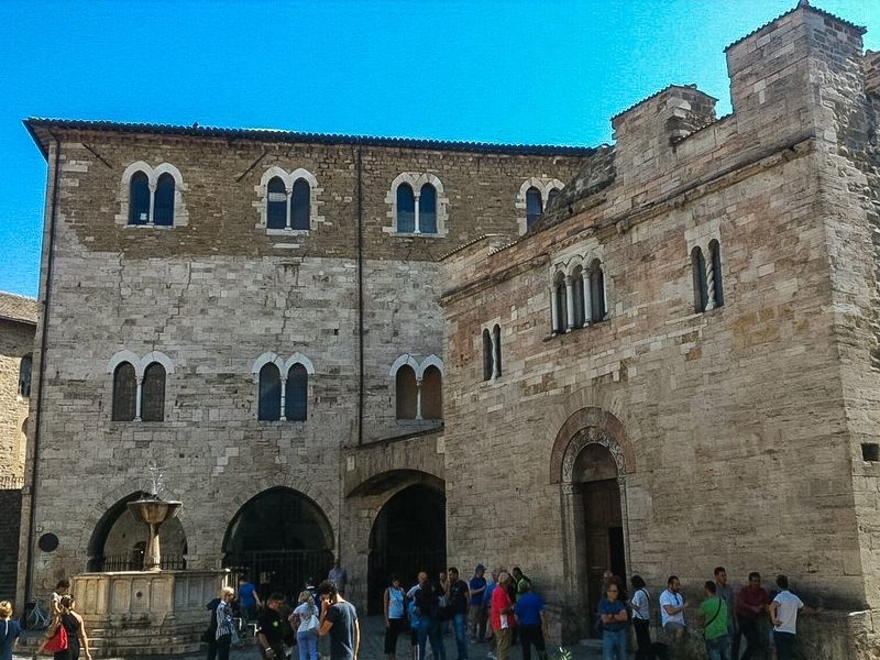 La piazza principale di Bettona, borgo da visitare in provincia di Perugia. In primo piano sulla sinistra la fontana medievale, sulla destra invece l'ingresso ad uno dei tanti palazzi del borgo.