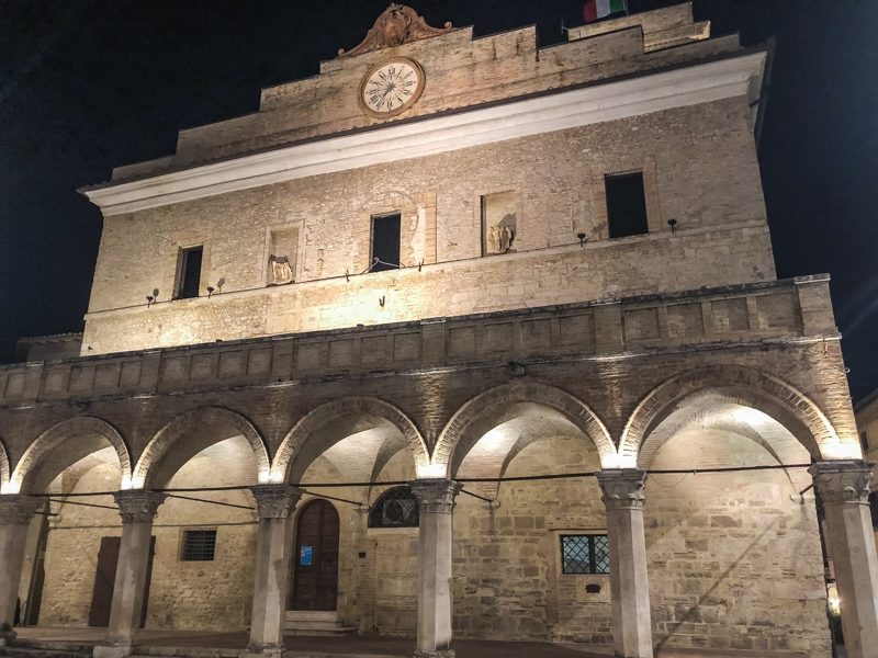 Un primo piano sul palazzo comunale di Montefalco con la sua bellissima loggia arcata sormontata da un terrazzino. Sulla sommità dell'edificio un orologio scagliona il tempo agli abitanti.
