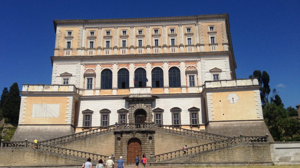 L'imponente Palazzo Farnese a Caprarola di cui spiccano la meridiana sulla sinistra e la grande scalinata a due rampe che accompagna al portone d'ingresso della struttura.