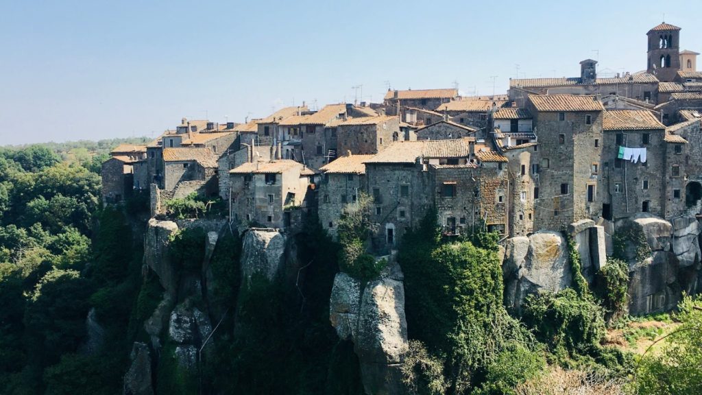 Il grande sperone tufaceo su cui sorge il borgo di Vitorchiano (Viterbo). Il borgo è costituito da tante casette in pietra tufacea. Lo sperone è circondato da alberi e verde vegetazione.