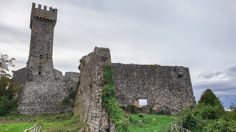 Ciò che rimane dell'antico castello di Radicofani con in primo piano i resti ancora in piedi delle mura difensive mentre sullo sfondo l'alto mastio merlato.