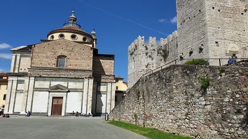 la basilica di santa maria delle carceri di prato con la sua struttura molto semplice in marmo e la cupoletta a volta. Sulla destra si intravede parte delle mura del castello dell'imperatore.