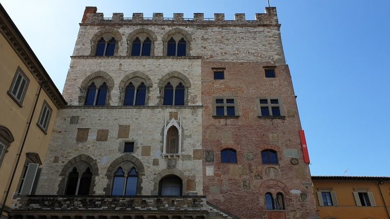 l'imponente struttura duecentesca del palazzo pretorio di prato costruito con mattoni rossi e con il tetto merlato. In primo piano le scalinate che portano all'ingresso del museo civico.