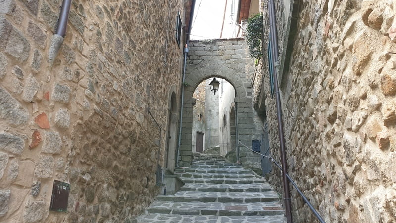 uno scorcio su una piccola strada stretta medievale fatta di mattoni e pietre all'interno del borgo di montelaterone