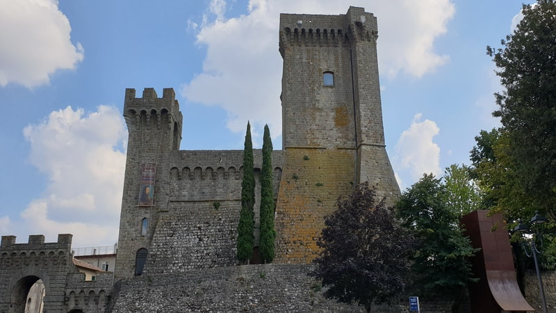 sulla destra la porta di ingresso medievale al centro di piancastagnaio mentre al centro della foto le due torri dell'antica rocca medievale con i loro grandi merli