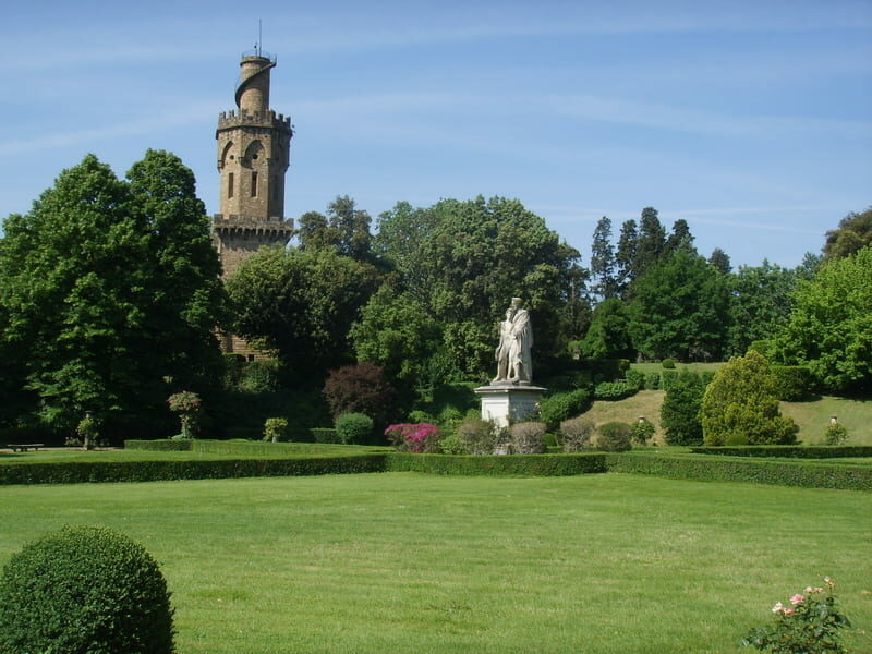 un grande prato verde con in fondo una statua neoclassica che si trova all'interno del giardino torrigiani. Sullo sfondo si vede far capolino tra gli alberi l'alto torrino