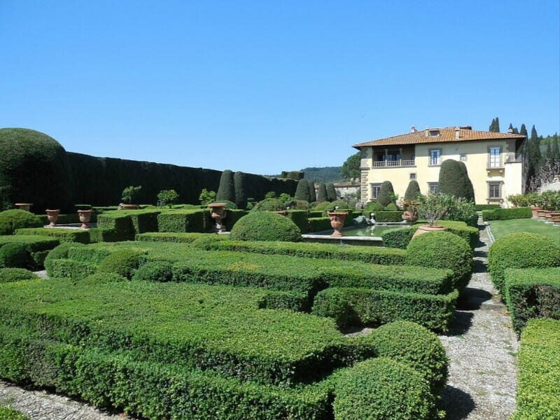 le alte siepi verdi del giardino di villa gamberaia che formano un labirinto e si vede sullo sfondo l'edificio padronale. Nel mezzo un piccolo laghetto d'acqua