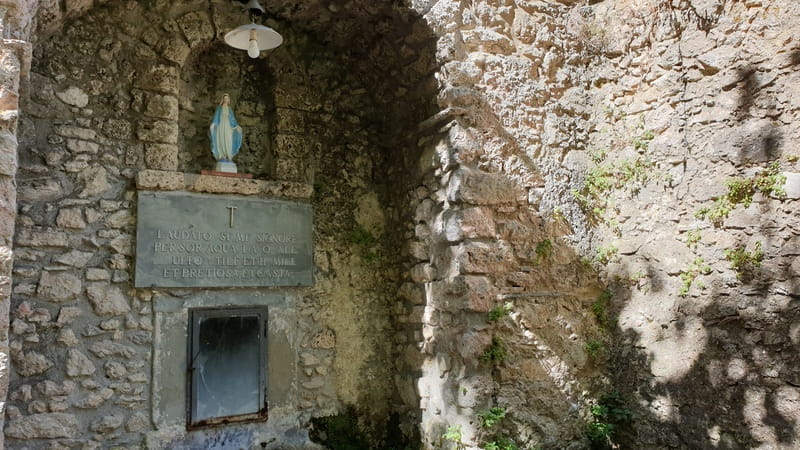 la fontana all'ingresso dell'eremo di calomini con in alto la statuetta della madonna e sotto un effige che ricorda una delle leggende sull'apparizione. Sotto tre fontane