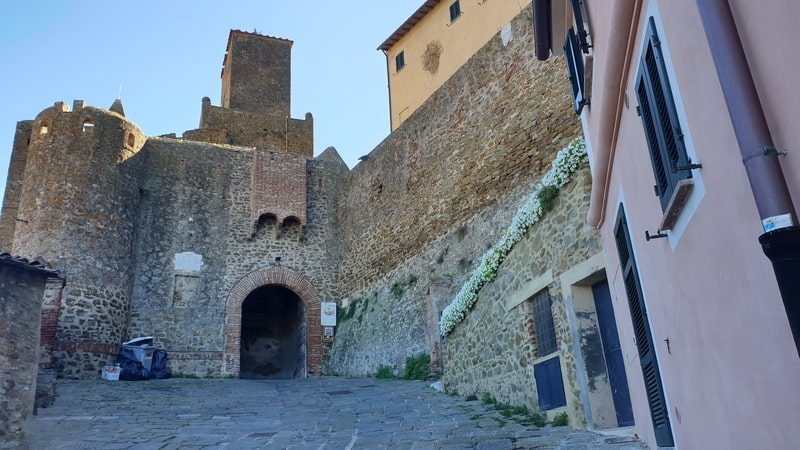 l'ingresso al centro storico di Castiglione della Pescaia tramite il sottopassaggio della torre dell'orologio che svetta altissima in primo piano