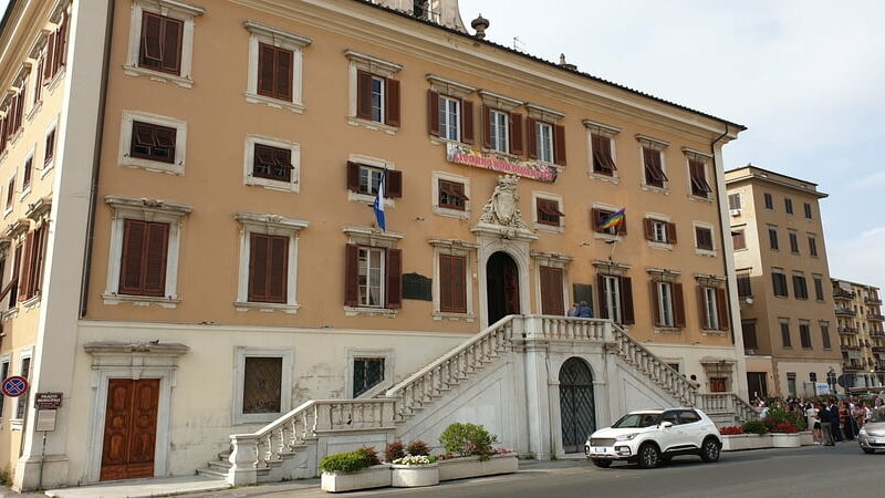 il palazzo comunale di livorno con colore arancione e in primo piano la doppia scala marmorea che porta al portone di ingresso
