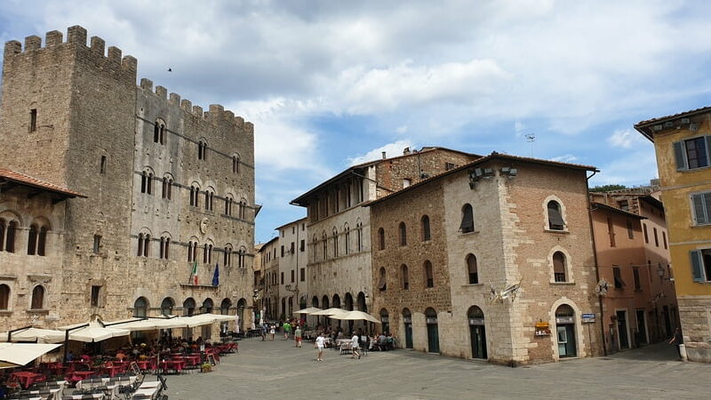 piazza garibaldi di massa marittima con sulla destra gli edifici che compongono il palazzo comunale e sulla sinistra altri edifici medievali e i ristoranti