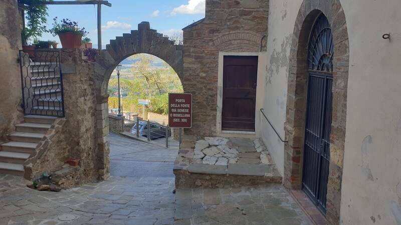 una porta laterale antica d'ingresso al centro storico di Scarlino. L'arco è molto grande e sullo sfondo si intravede il verde della campagna della maremma toscana