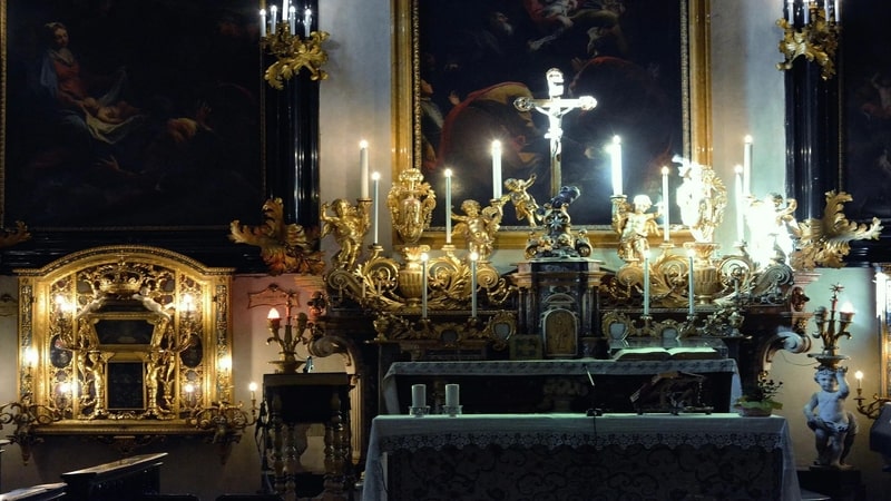 un primo piano sull'altare della cappella dei mercanti di torino con al centro il grande crocifisso e sulla destra la piccola porta del tabernacolo in oro