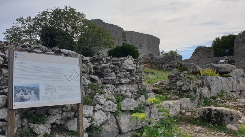 una vista ravvicinata sui ruderi del capitolium dell'antica città di cosa con le mura e sullo sfondo il blu che si vede della laguna