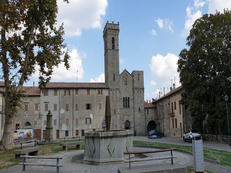 un primo piano sull'abbazia di san salvatore con la sua struttura medioevale e l'alta torre. In primo piano davanti una grande fontana