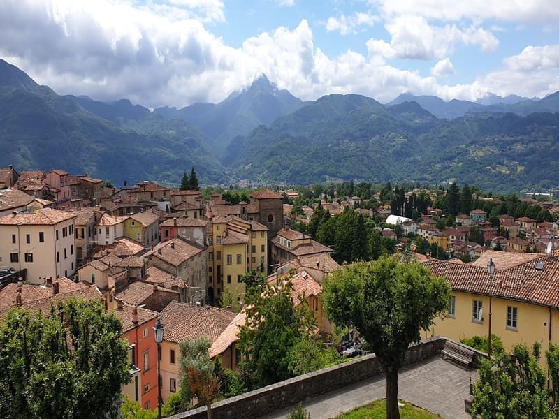 una splendida vista panoramica sulla città di barga, uno dei borghi toscani da vedere, e sulle grandi montagne delle alpi apuane che raggiungono le nuvole sul cielo