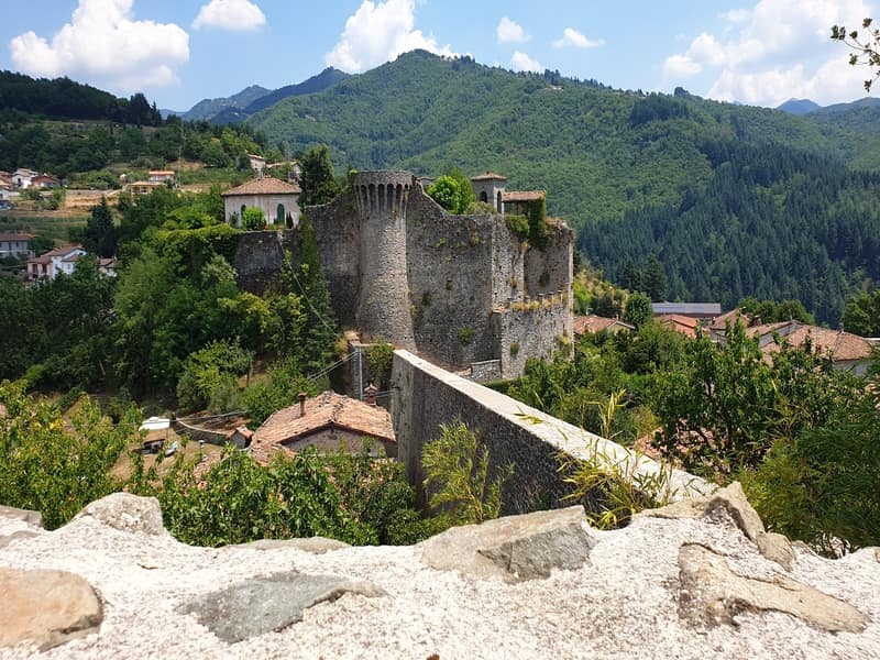 una vista sulla rocca medievale di castiglione di garfagnana dalla terrazza panoramica del borgo. Si vede sullo sfondo e intorno alla rocca il fitto verde delle vegetazione della garfagnana