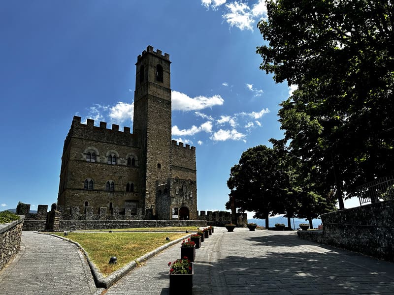 una vista da lontano sul castello dei conti guidi di poppi con la sua enorme torre difensiva al centro. Spiccano le alte guglie ed il ponte levatoio ad ingresso del castello