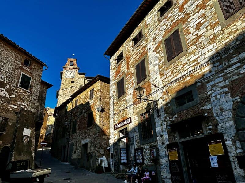 uno scorcio su di una strada del centro storico di campiglia marittima con tutti i suoi edifici in pietra antica e la torre dell'orologio che svetta