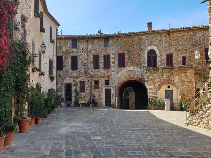 Piazza del Castello a Montemerano con fiori e vegetazione, un angolo romantico che rappresenta perfettamente cosa vedere in Maremma