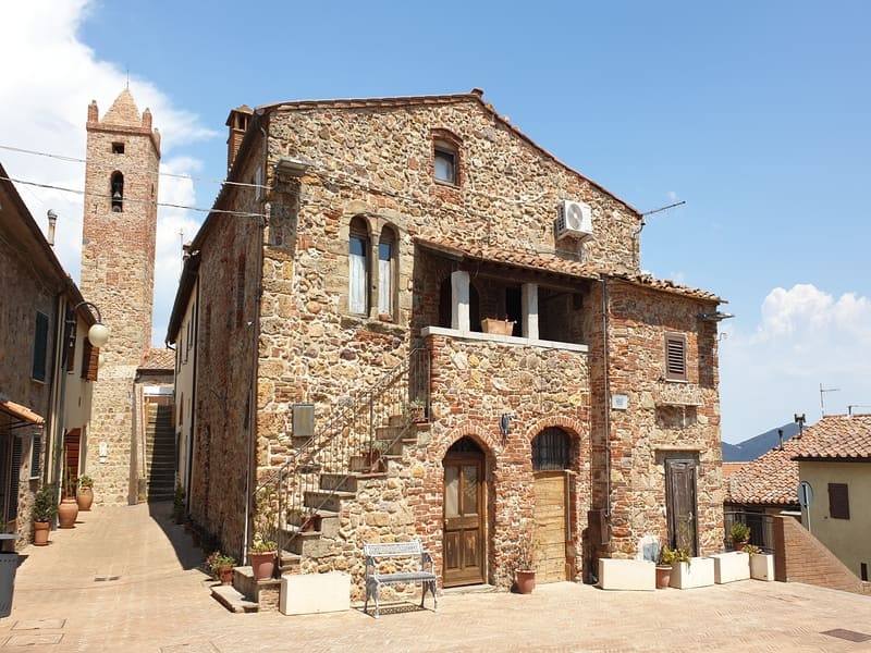 Edificio storico in pietra con torre campanaria sullo sfondo a Montepescali, uno dei borghi panoramici della Maremma