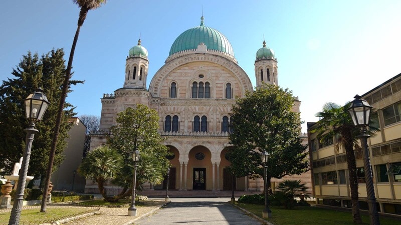 Facciata monumentale della sinagoga di Firenze con la cupola verde rame che domina il panorama urbano.