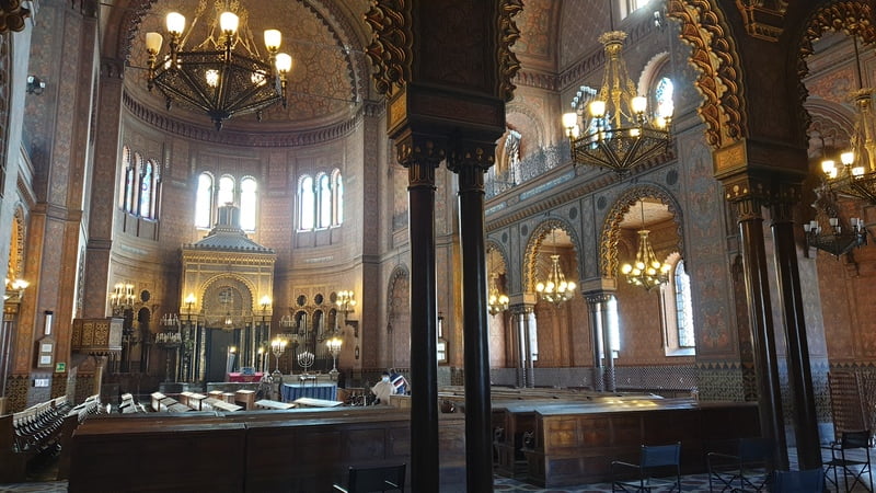 Interno completo della sinagoga di Firenze con navata centrale, colonne decorate, mosaici e lampadari imponenti.