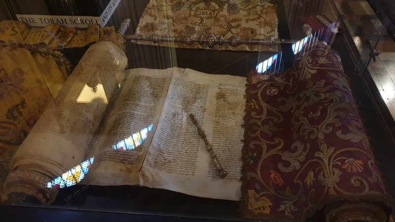 Antico rotolo della Torah esposto nel Museo ebraico, testimonianza della tradizione religiosa ebraica a Firenze.