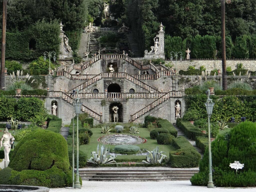 Le due rampe di scale con i tre pianerottoli che portano alla villa garzoni di collodi. In ogni piano c'è una statua centrale e due laterali. In primo piano poi parte del disegno formato con i cespugli del giardino.
