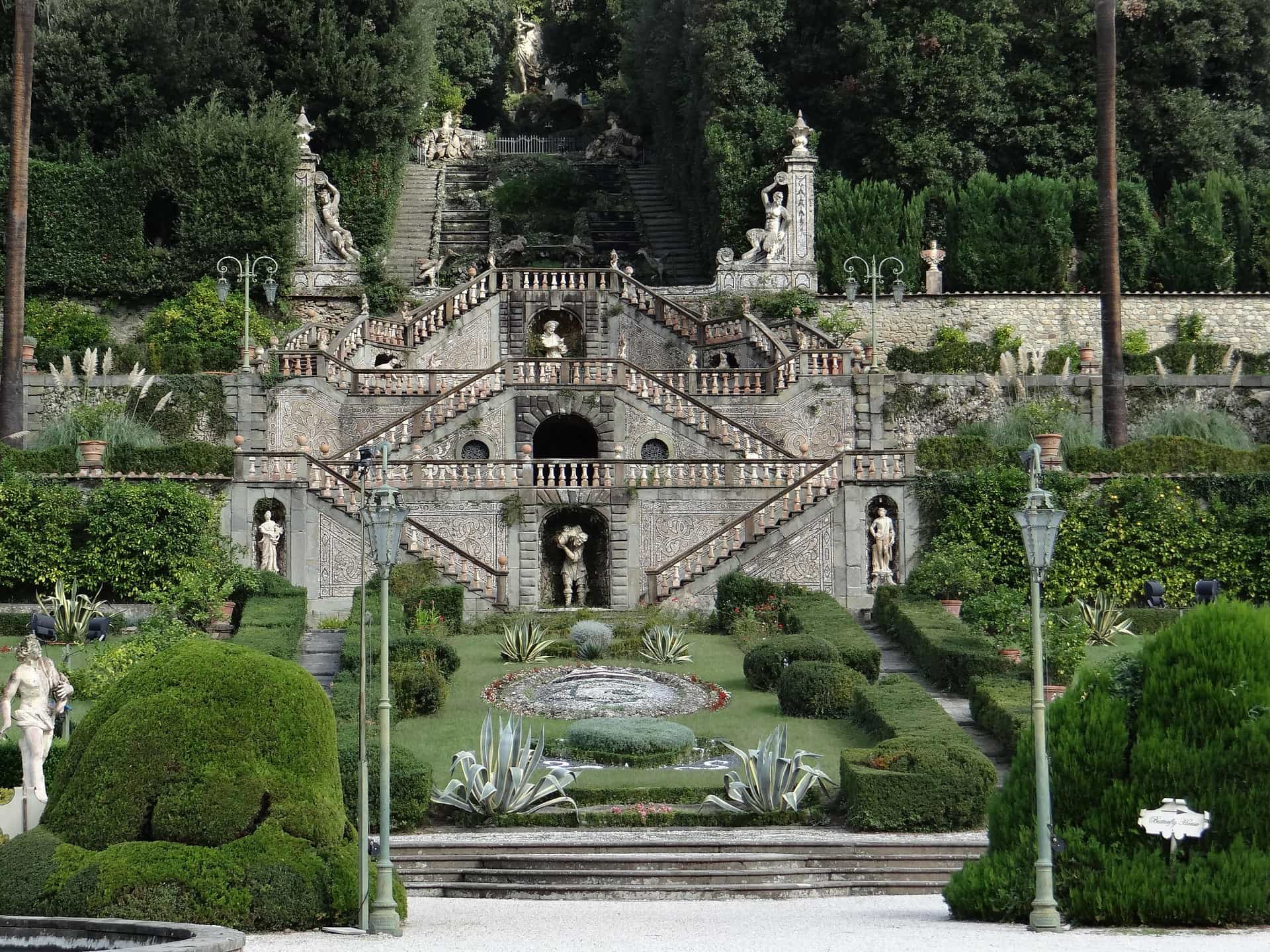 Le due rampe di scale con i tre pianerottoli che portano alla villa garzoni di collodi. In ogni piano c'è una statua centrale e due laterali. In primo piano poi parte del disegno formato con i cespugli del giardino.